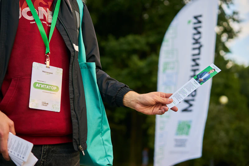 An attendee holding up a conference badge on a lanyard