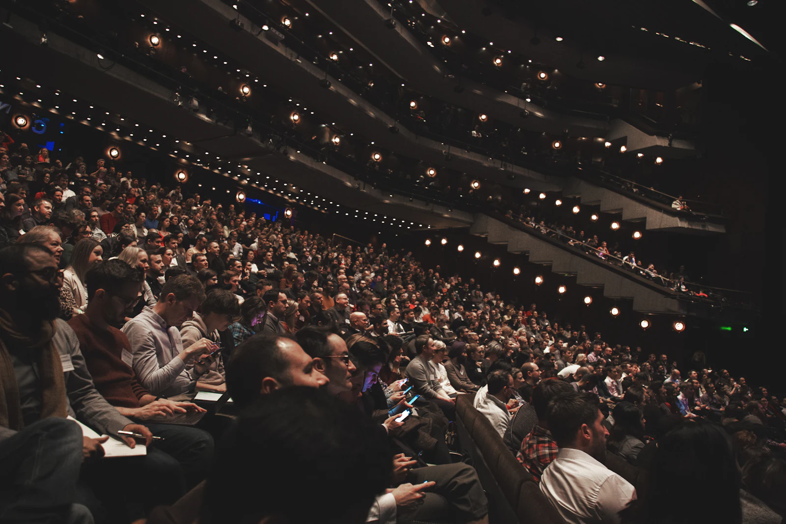 A full auditorium watching a speaker on a large stage