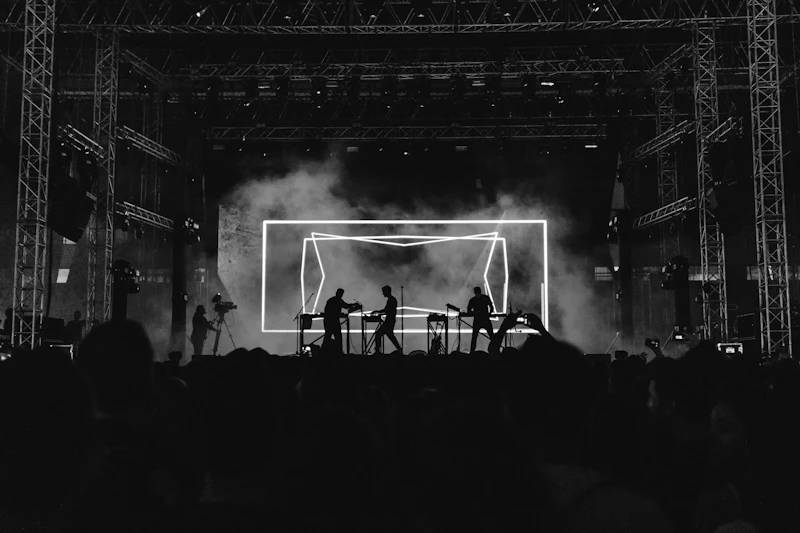 A stage lit by beams of white light over a crowd